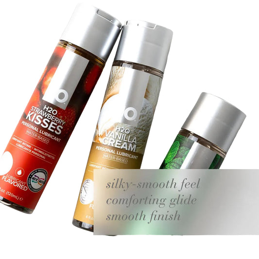 Three personal lubricant bottles with labels on a textured white background