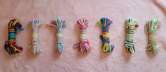 A collection of colorful bamboo rope displayed against a pink blanket background, in various shades and patterns.