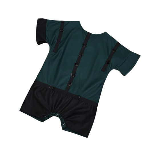 Green and black romper with restraining rings and snap crotch on a bed with purple silk sheets