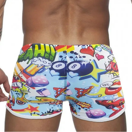 Colorful swim shorts with cartoon designs worn by a person on a white background