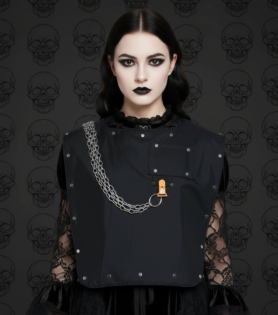 Black adult sized bib with metal studs and chain on a goth girl in front of black skulls
