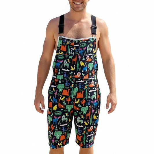 Colorful animal-patterned overalls hanging on a hanger against a floral curtain background.