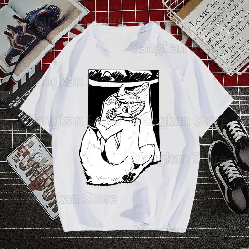 White t-shirt with black cat graphic on a grid surface with shoes and books.