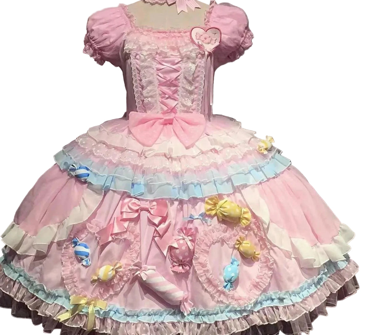 Pink and pastel dress with decorative elements on a mannequin against a dark background