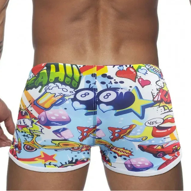 Colorful swim shorts with cartoon designs worn by a person on a white background
