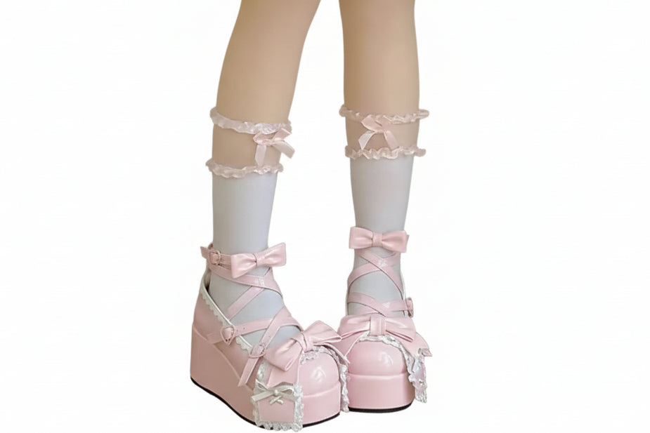 Pastel pink platform shoes with bows and white stockings on a neutral background