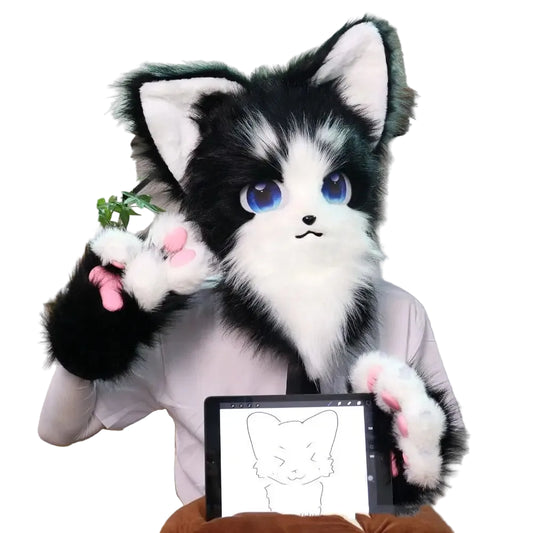 Black and white plush cat toy with blue eyes sitting on a chair next to a tablet displaying a drawing of a cat.