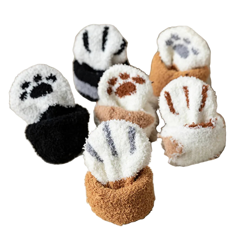 Set of plush paw-shaped items in various colors on a soft fabric background