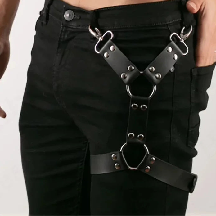Person wearing black pants with metal harnesses on a plain background