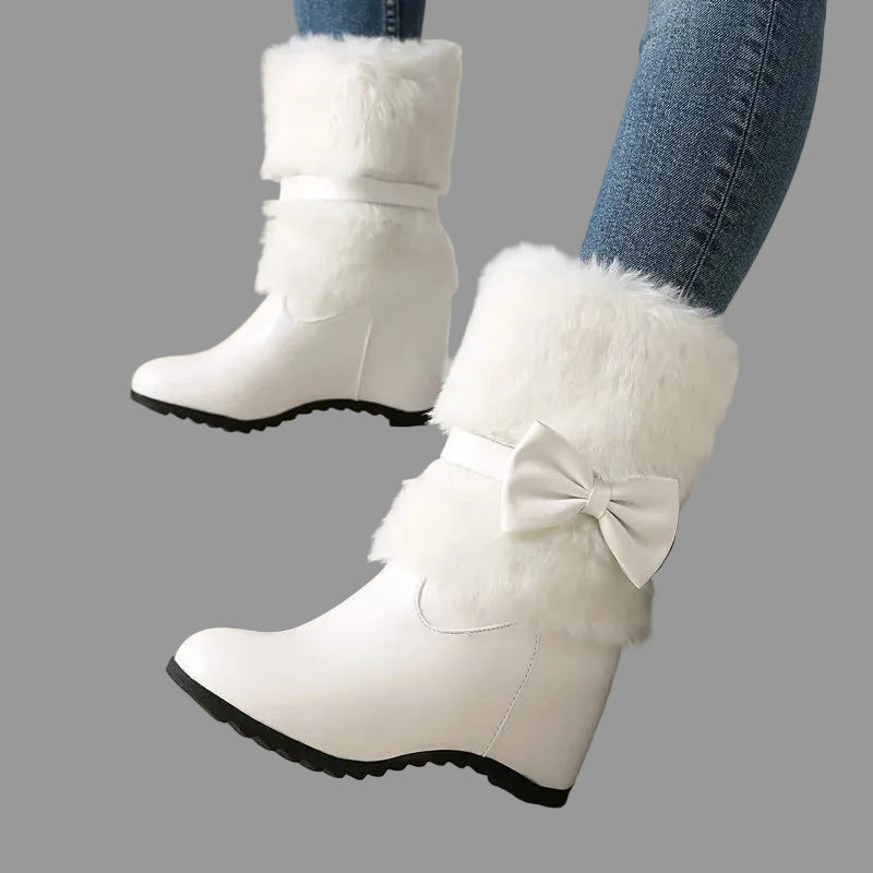 White winter boots with fur and a bow on a neutral background