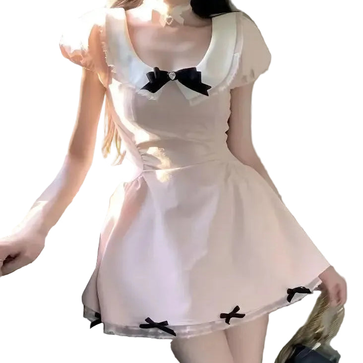 Person wearing a white dress with black bows in a room.