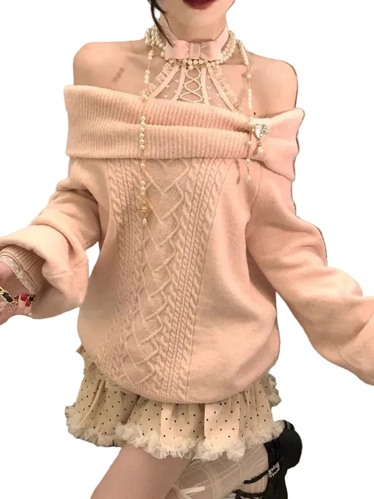 Person wearing a pink sweater with intricate patterns and a pearl necklace.