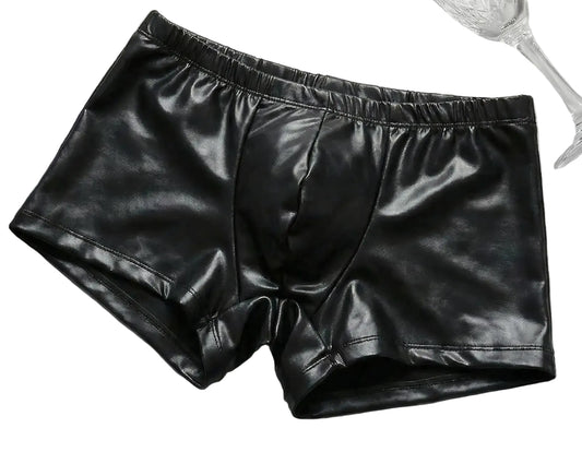 Black leather shorts on a textured white surface with a glass of champagne and newspaper.
