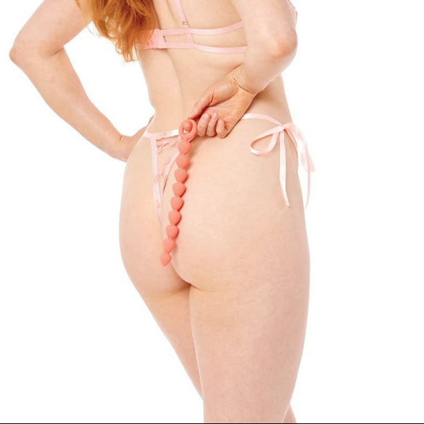 Woman wearing a sheer pink lingerie set on a white background