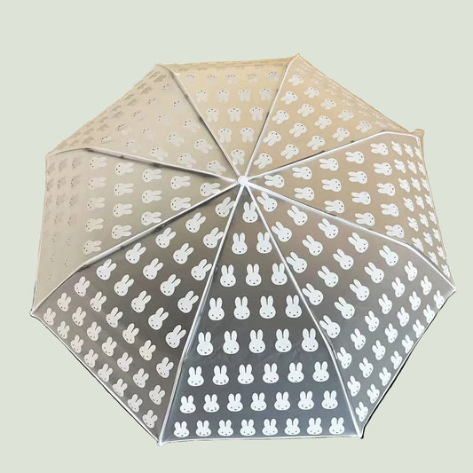 Transparent umbrella with white bunny pattern on a wooden surface