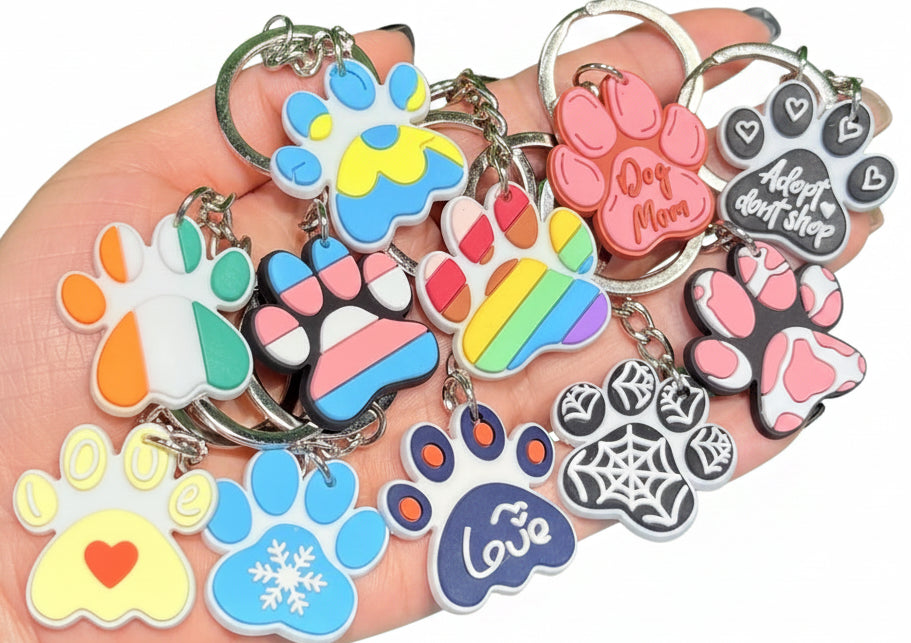 Collection of colorful paw print keychains held in a hand with a green grass background
