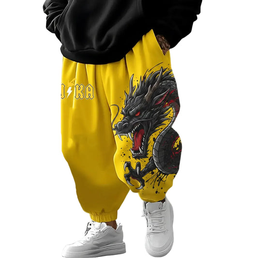 Person wearing yellow pants with a dragon design and white sneakers on a neutral background
