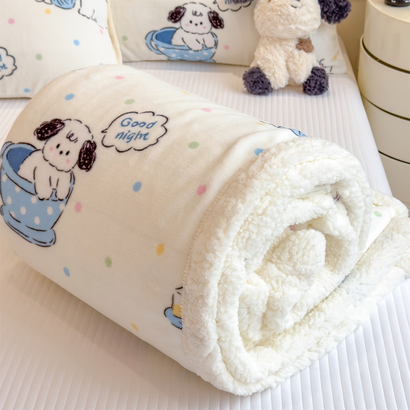 Rolled-up blanket with cartoon dog design and 'Good night' text on a soft surface.